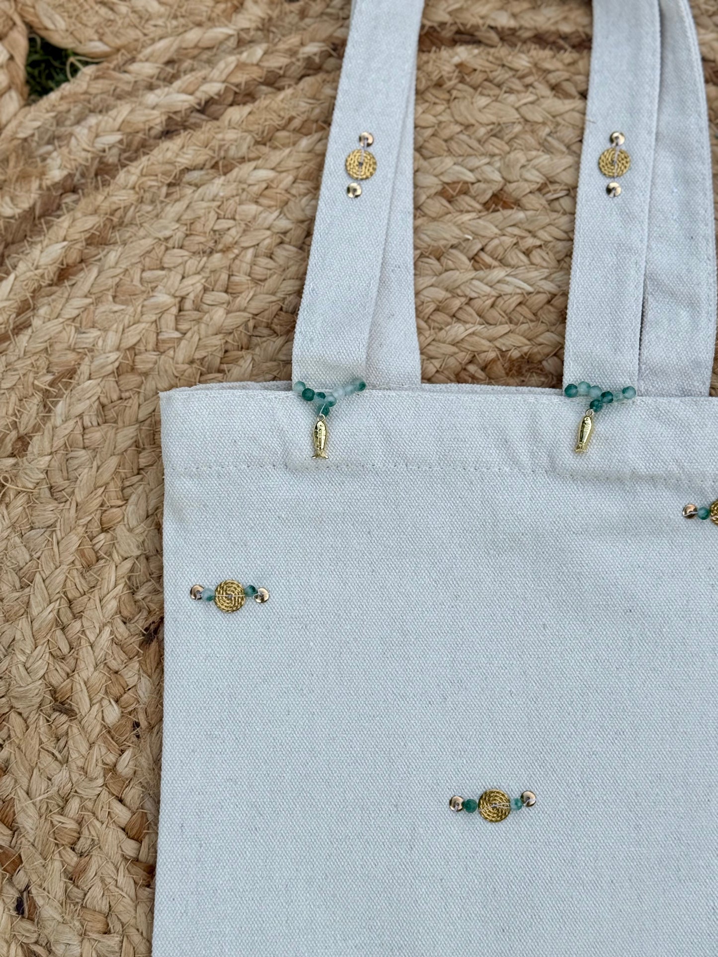 Light blue tote bag with decorative buttons on a woven surface