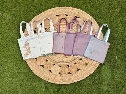 Set of small tote bags in various colors on a woven mat
