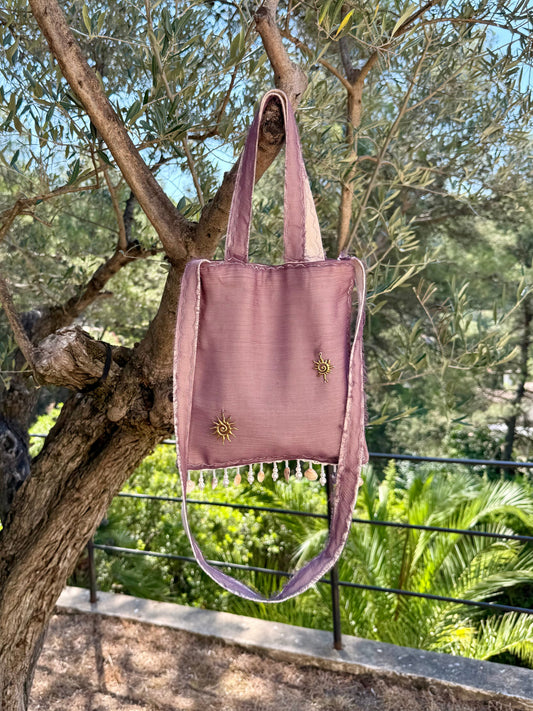 Pink tote bag hanging from a tree branch with a natural background