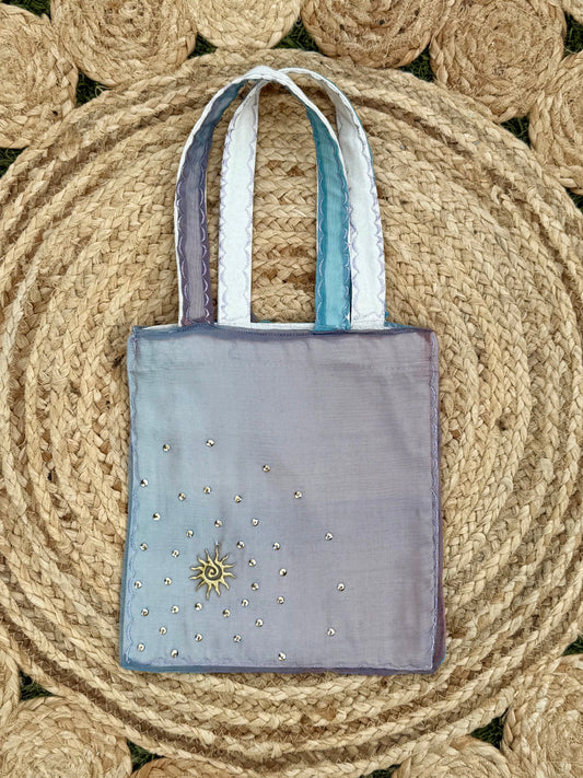 Purple tote bag with decorative elements on a woven mat