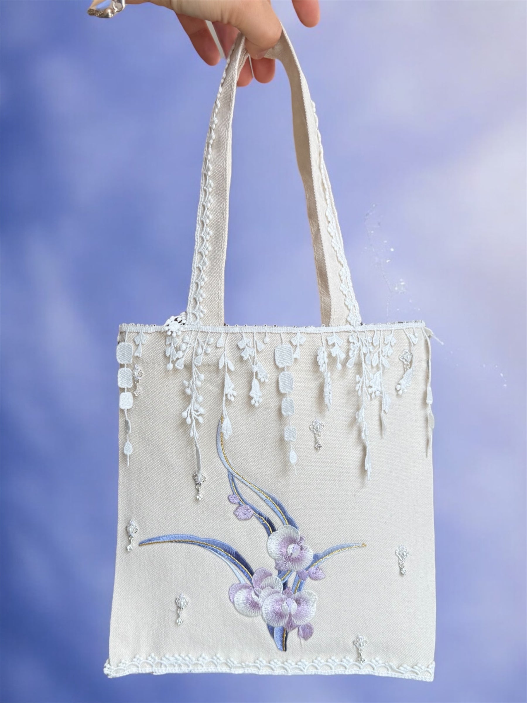 Handheld tote bag with floral design against a blue background